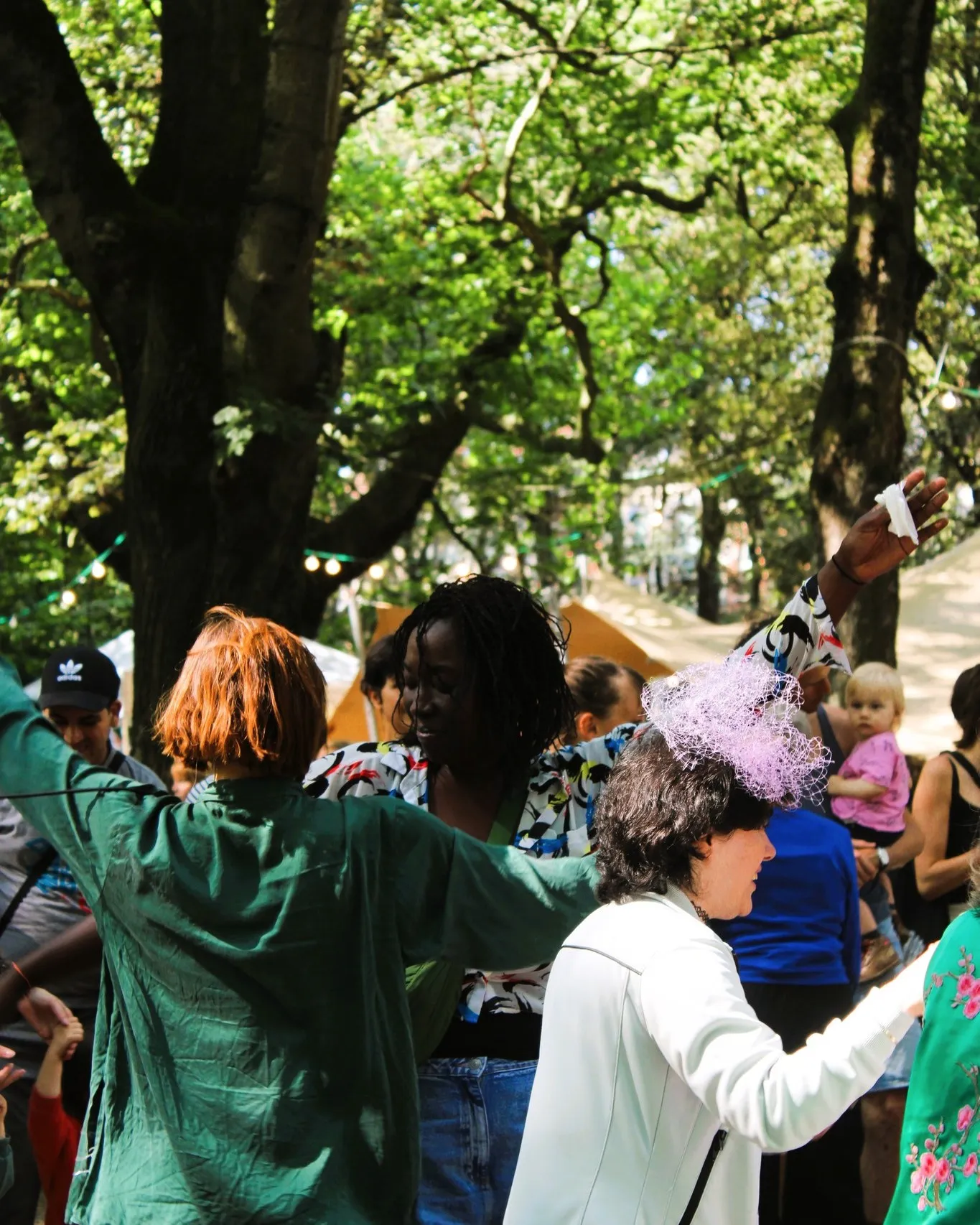 Groupe de personnes de différents âges dansant ensemble entre les arbres du parc.