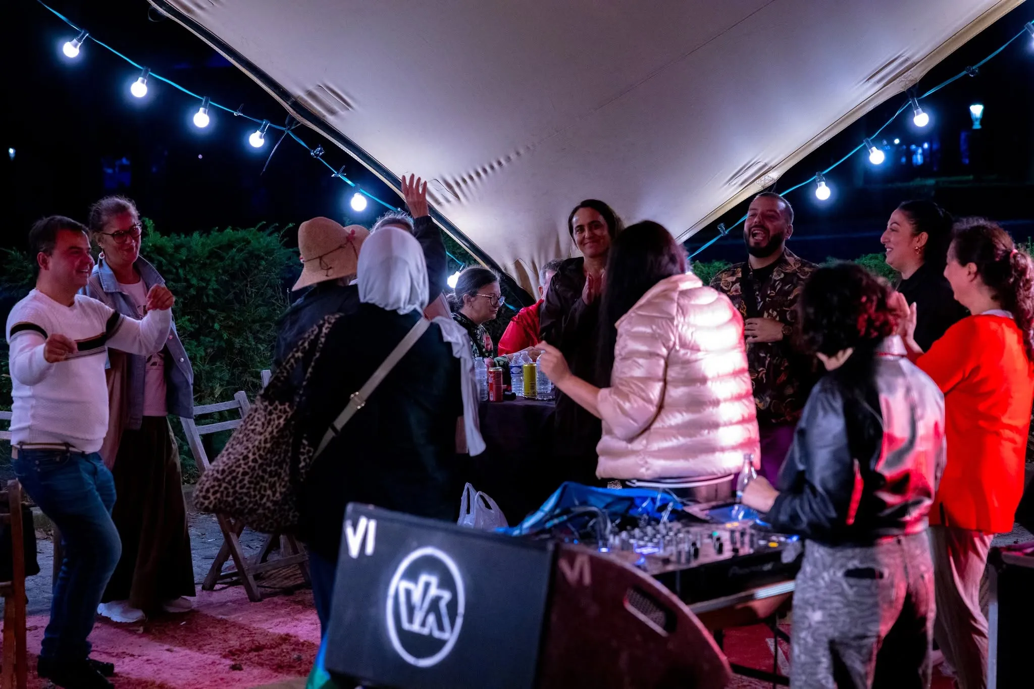 Des gens dansent sous les guirlandes près de la cabine du dj, tard dans la soirée.