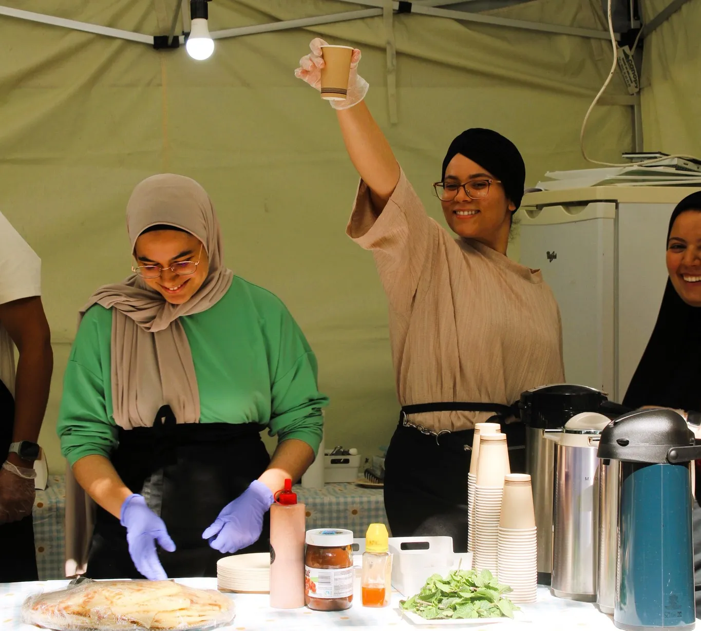 Un stand alimentaire sous une tente à Plazey : deux femmes préparent et servent à manger.