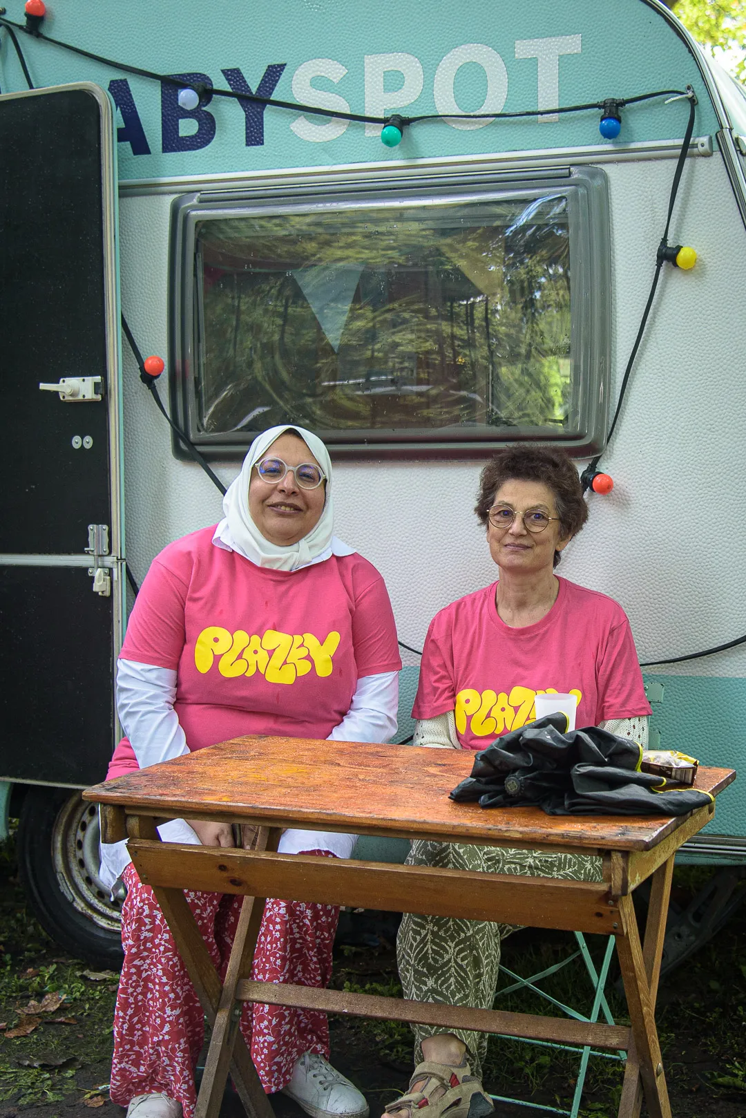 Twee vrijwilligers in roze Plazey-t-shirt voor de Baby Spot-caravan.