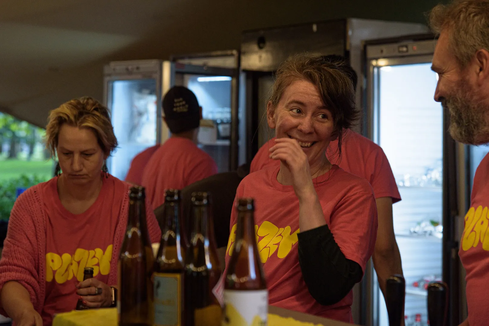Des bénévoles en t-shirt rose Plazey derrière le bar.